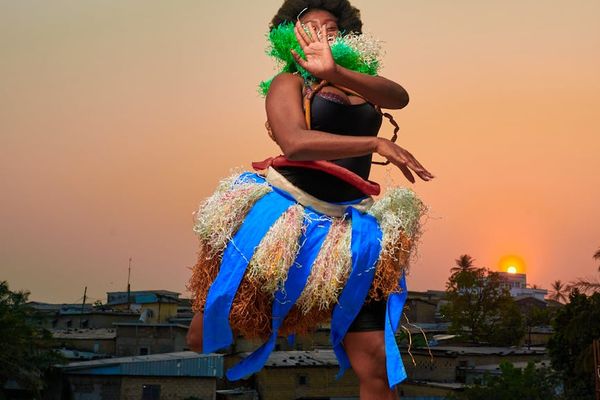 Person in a dynamic, flowing movement pose outdoors at sunrise.